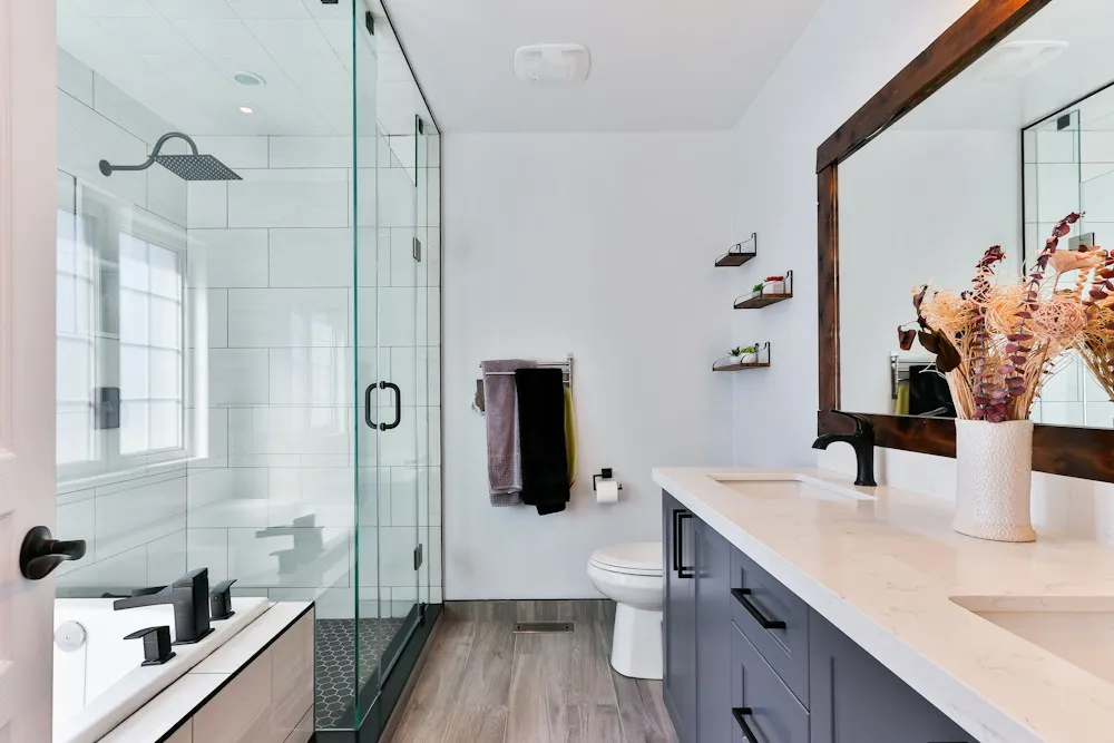 Compact modern bathroom with a glass shower, pale vanity and a large framed mirror.