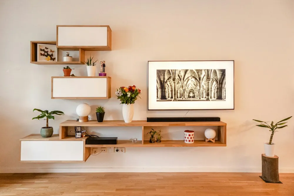 Minimal floating shelves styled with art, ceramics and plants against a pale wall.