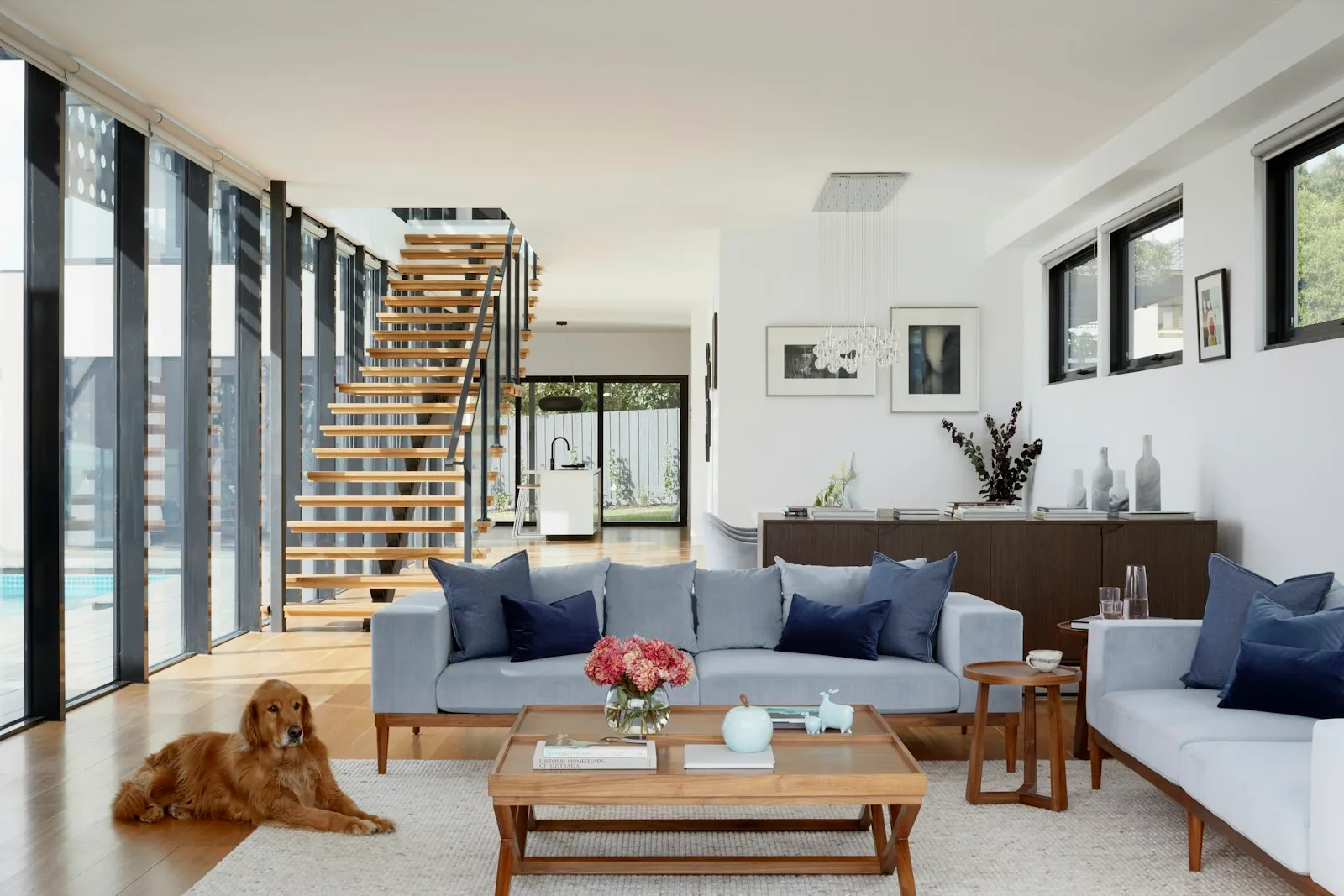 Bright double-height open-plan interior with a timber staircase, mid-renovation with finished joinery.